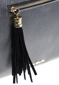 Zwarte leerachtige tas met gouden rits en een zwarte suède franje aan de rits.