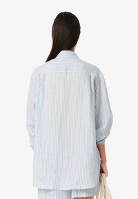 Camisa de manga larga a rayas azul claro y blanca con cuello, corte relajado y mangas remangadas; confeccionada en una tela suave y ligera.