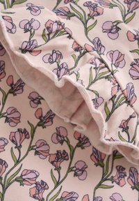 Blommönstrad tyg med ljusrosa bakgrund, gröna stjälkar och lila blommor. Volangkant ger texturdetalj.