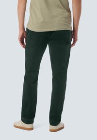 Donkergroene corduroy broek met een rechte pasvorm, voorzien van een zachte textuur en een subtiele glans, gecombineerd met lichtgekleurde sneakers.