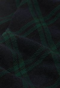 Tessuto scuro con un motivo a quadri verdi, caratterizzato da un materiale a maglia testurizzato. Il design presenta strisce incrociate in tonalità di verde e blu navy.