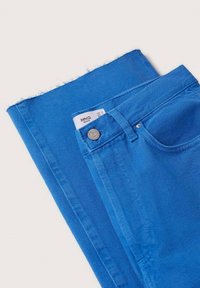 Jeans en denim bleu à coupe droite. Dotés d'un bouton en métal, de poches et d'un détail de ourlet effiloché. Étiquette visible à l'intérieur de la ceinture.