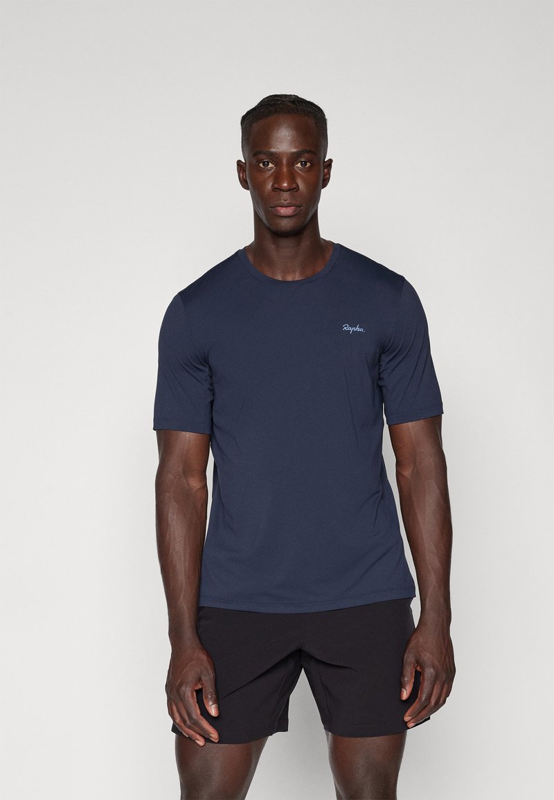 Mørkeblå kortærmet t-shirt med rund hals og diskret logo-detail på brystet, lavet af glat, let stof, parret med sorte shorts.