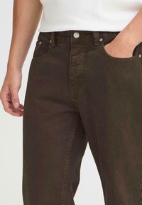 Mørkebrune denimjeans med et klassisk fem-lomme-design, med sølvfarget maskinvare og rett ben. Standard liv med knapplukking.