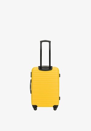 Valise rigide jaune avec des rainures verticales, poignée télescopique noire, poignée de transport latérale et quatre roulettes.