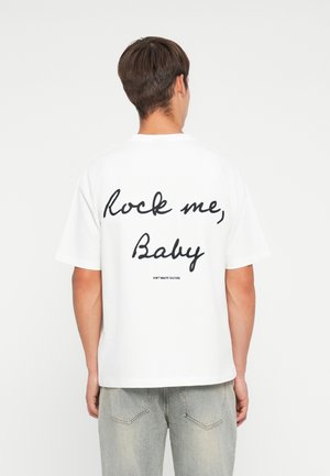 Witte katoenen t-shirt met korte mouwen, voorzien van grote zwarte cursieve tekst op de achterkant met de tekst "Rock me, Baby" en een klein logo eronder.