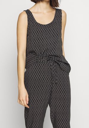 Zwarte mouwloze jumpsuit met grijs diamantpatroon, ronde halslijn en bijpassende stoffen riem gestrikt in de taille, gedragen door een staand persoon.