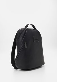 Black leather backpack with a smooth texture, featuring a front zip pocket, padded straps, and a branded rectangular patch.