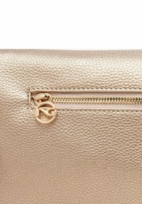 Guldtekstureret læderclutch med en diskret lynlås og cirkulær logo-træk. Overfladen viser et fint kornmønster for ekstra detaljering.