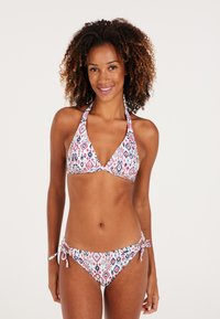 Driekhoek bikini in het wit met meerkleurige geometrische patronen. Halternek, gestrikte zijkanten en een gladde stoftextuur.