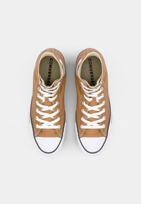 Bruine canvas hoge sneakers met witte veters, rubberen neuskap en zwarte accenten. Het interieur heeft een gedrukt logo op de inlegzool.
