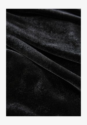 Černý sametový materiál s měkkou, hladkou strukturou, s mírným leskem a subtilem odrazem světla na svém povrchu.