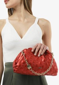 Borsa a tracolla rossa e piumosa realizzata in materiale trapuntato, con una cinghia in catena dorata e un ciondolo quadrato con dettagli del logo.