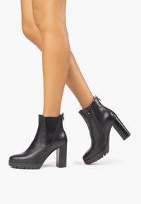 Czarne skórzane botki za kostkę z przetartym bokiem, masywnym obcasem, gładką fakturą i zamkiem błyskawicznym po boku dla łatwego zakładania. Podeszwa z rowkami zapewnia przyczepność.