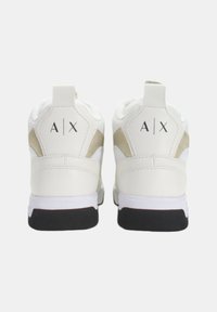 Sneakers bianchi con finitura in pelle liscia, dettagli in suede beige, lacci piatti e suole in gomma nera. Presentano un logo sul tallone.