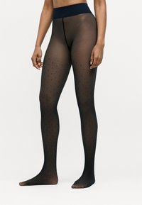 Collants noirs transparents avec de petits pois noirs, dotés d'une large taille opaque et d'une texture lisse et douce.