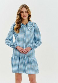 Svetlomodré a biele kárované šaty s volánovým golierom, dlhými rukávmi, zapínaním na gombíky a vrstveným dizajnom sukne.