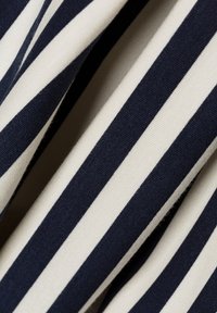 Marineblau- und cremegestreifter Stoff mit einer glatten, strukturierten Oberfläche, die gleichmäßig verteilte vertikale Streifen auf einem sanften Gewebe aufweist.
