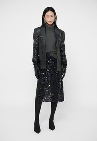 Blazer de couro preto, gola alta cinza, saia midi preta com lantejoulas, luvas pretas, textura transparente, saltos pontiagudos pretos, design minimalista.