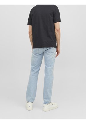 Czarny t-shirt z krótkim rękawem, jasnoniebieskie jeansy o prostych nogawkach oraz białe trampki. Gładkie faktury, prosty design, brak widocznych wzorów i logo.