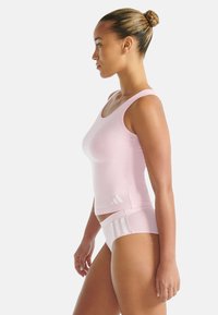 Lichtroze sportieve tanktop met een ronde halslijn en witte logodetails, gecombineerd met bijpassende roze slips met witte accenten.