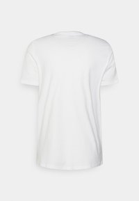 Camiseta blanca de algodón con mangas cortas y cuello redondo, que presenta una textura suave y un diseño simple y sin adornos.