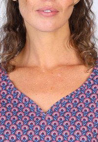 V-Ausschnitt-Oberteil mit floralem Muster in Pink und Blau auf navy Hintergrund; weicher Stoff mit glatter Textur; ärmelloses Design.