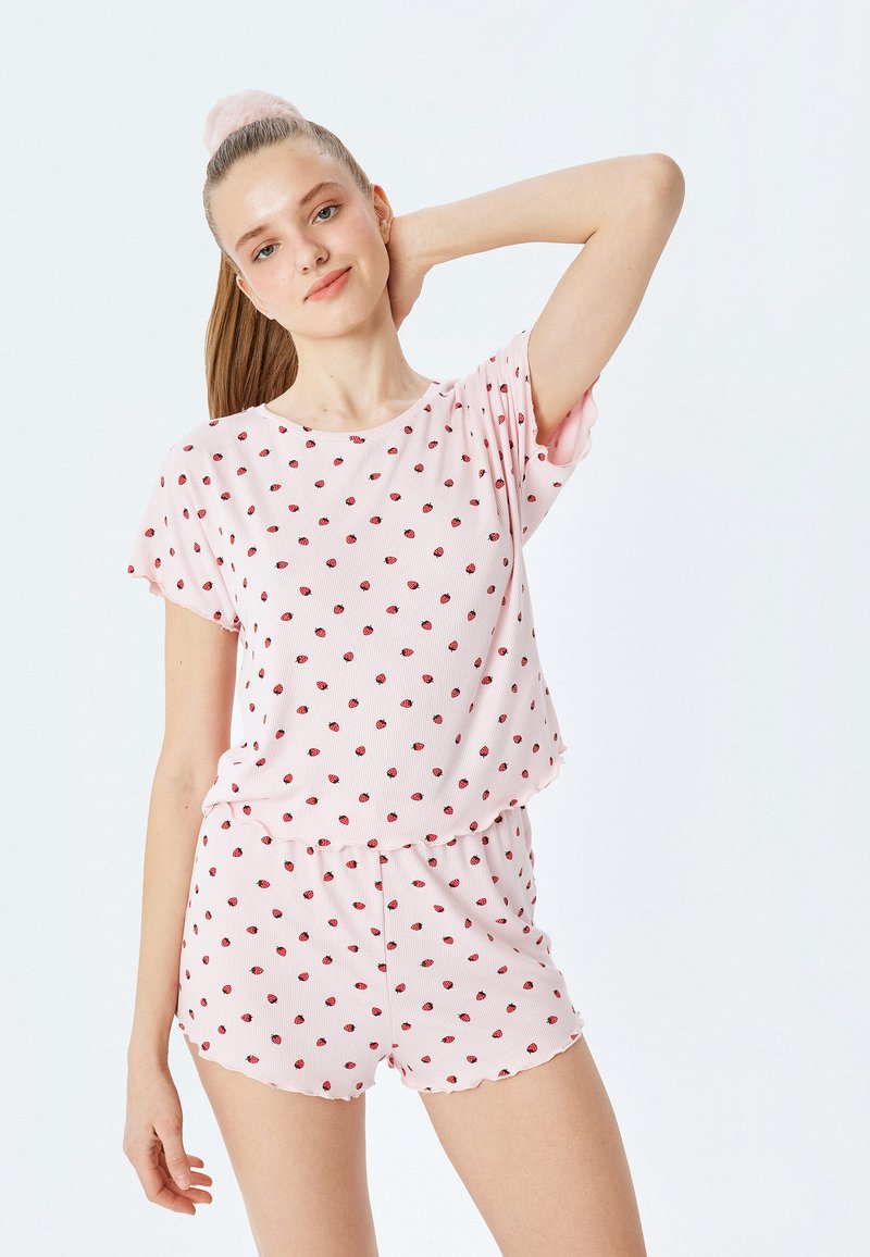 Ensemble de vêtements de détente rose clair avec un petit motif à pois rouge. Haut à manches courtes avec col rond, associé à un short avec un ourlet festonné.
