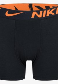 Black cotton boxer shorts with orange Nike logo on the waistband, featuring a smooth texture and a fitted design.