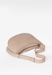 Beige Lederhandtasche mit geschwungener Form, Reißverschluss und verstellbarem Riemen. Glatte Textur mit dezenten Nahtdetails.