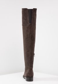 Knöchelhohe braune Wildlederstiefel mit gespaltenem Schaft, seitlichem Reißverschluss und flacher Sohle. Geschmeidige Textur mit weichem Finish.