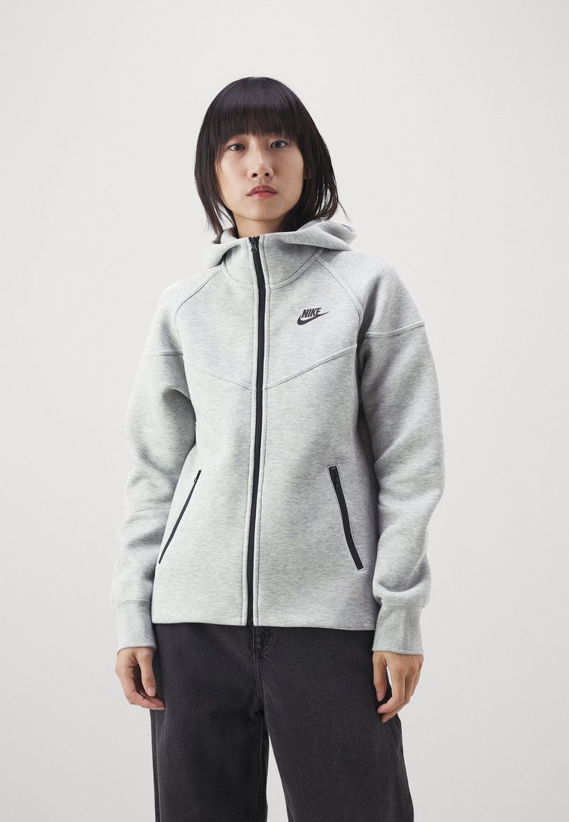 Grau zip-up Kapuzenpullover von Nike; mit schwarzen Akzent-Reißverschlüssen, Logo auf der Brust und einem strukturierten Design aus texturiertem Stoff.