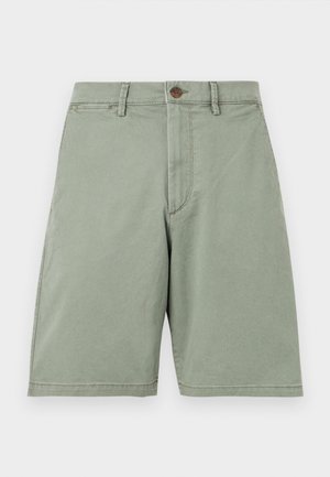 Lichtgroene knielange shorts met een knoop- en ritssluiting, riemlussen en zijzakken, getoond tegen een effen achtergrond.