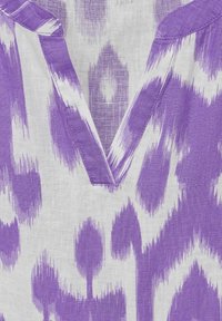 Tela de patrón púrpura y blanca con escote en forma de V, que presenta un tejido de lino texturizado y motivos abstractos en diferentes tonalidades.
