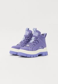 Sneakers high-top viola in tela con una suola in gomma bianca spessa. Presentano lacci, dettagli del logo e una finitura testurizzata.