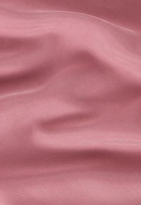 Sile pinkki kangas, jossa on hienovarainen kiilto ja herkkä rakenne, esittäen lempeitä taitoksia ja ryppyjä, jotka korostavat sen pehmeää laatua.