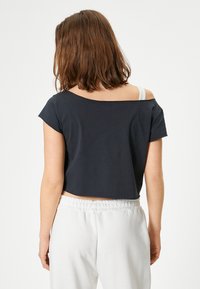 Zwarte cropped t-shirt met een brede ronde halslijn en korte mouwen, gecombineerd met elastische witte sweatpants. Soepele stof, relaxte pasvorm.