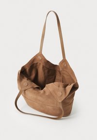 Bolso tote de ante marrón con una textura suave, que cuenta con dos asas largas, un interior espacioso y cierres a presión en los laterales.
