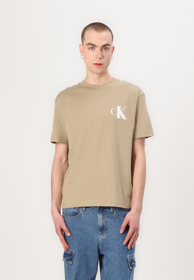 Šviesiai smėlinis medvilninis marškinėliai trumpomis rankovėmis, su apvalia iškirpte ir mažuoju baltu "cK" logotipu ant kairiojo krūtinės dalies. Kasdienis kirpimas.