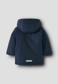 Chaqueta infantil de color azul marino con capucha, que presenta una textura suave, mangas cortas y un acento reflectante en la parte baja de la espalda.