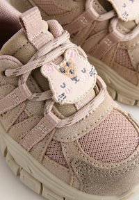 Baskets rose clair avec des textures en maille et en daim, présentant une appliqué en tissu d'une souris avec des détails brodés sur la zone des lacets.
