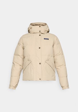 Giacca invernale imbottita beige con colletto alto, chiusura con bottoni a pressione, tasche frontali diagonali, polsini elasticizzati e piccolo logo Patagonia sul petto.