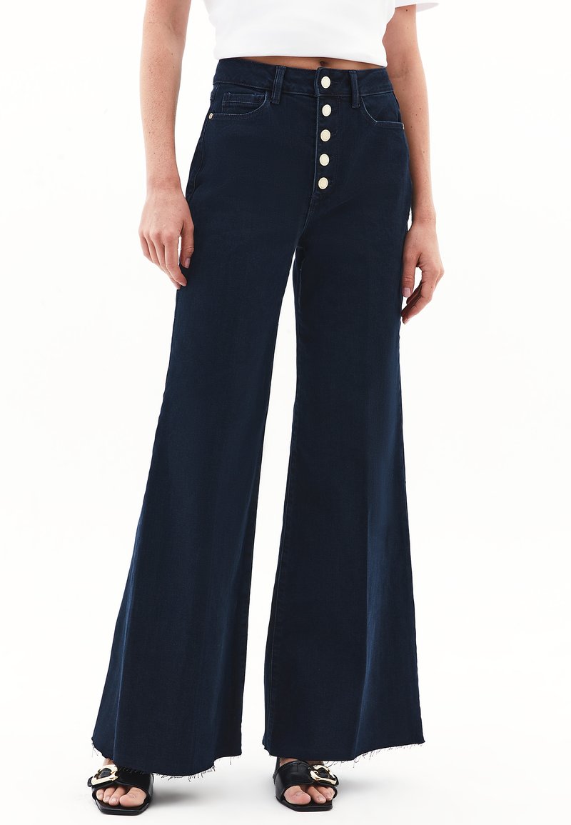 Spodenki dżinsowe o szerokich nogawkach w ciemnoniebieskim kolorze, z wysokim stanem i zapięciem na pięć guzików, z kieszeniami z przodu i surowymi końcami.
