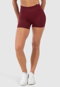 Bordeaux hoge taille shorts, gemaakt van rekbare stof, met een gladde textuur en strakke pasvorm, gecombineerd met witte sport schoenen.