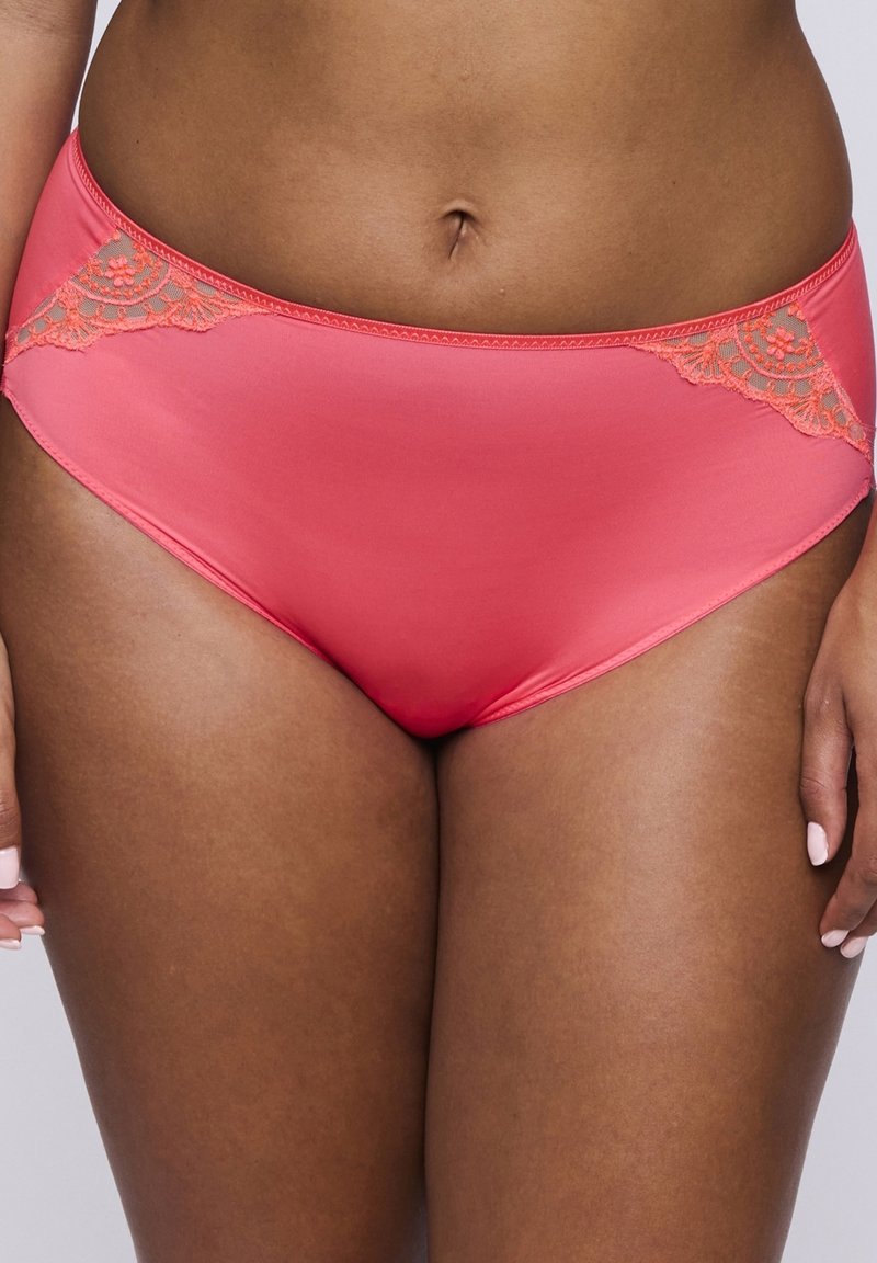 Biancheria intima color corallo con una texture liscia, caratterizzata da complessi dettagli in pizzo su un lato e dalla forma classica dei slip.