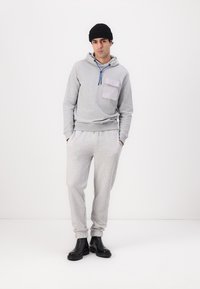 Gray cotton hoodie with a front pocket and blue drawstring, paired with matching gray sweatpants, complemented by black boots.