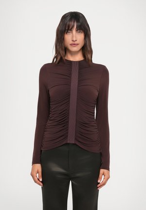 Mauve long-sleeve top with gathered detailing at sides and a vertical ribbed accent down the center; fabric appears smooth and fitted.