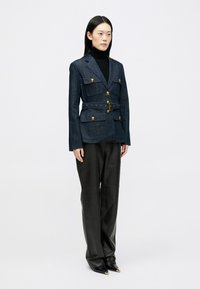 Blazer di denim con bottoni dorati, vita abbellita da una cintura e quattro tasche frontali. Abbinato a pantaloni in pelle nera e scarpe nere con punta. 