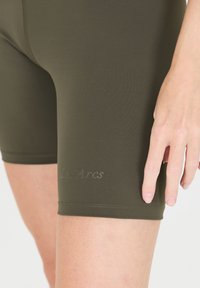 Shorts de performance vert olive en matériau extensible, présentant un design ajusté et un logo subtil "Les Arcs" embossé à l'ourlet.
