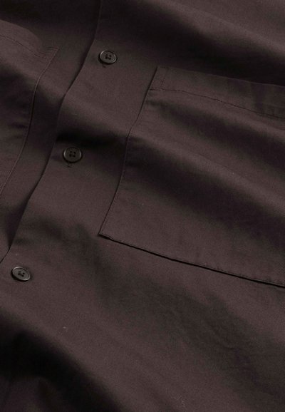 Mørkebrun skjorte med knaplukning lavet af glat stof, med en brystlomme, sorte knapper og en struktureret krave.